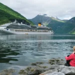 A traveler looking at a cruise ship in Norway, a helpful visual for the MyVikingJourney guide.