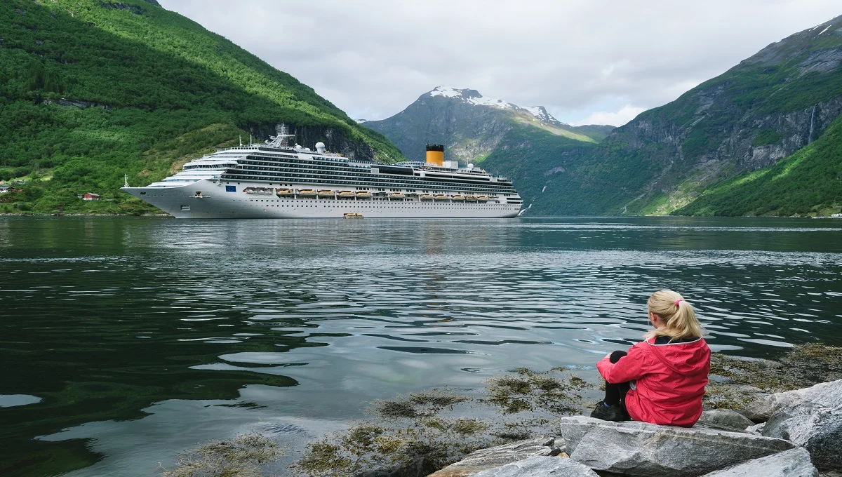 A traveler looking at a cruise ship in Norway, a helpful visual for the MyVikingJourney guide.