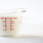 Transparent measuring jug showing cup and liter measurements for volume conversion.