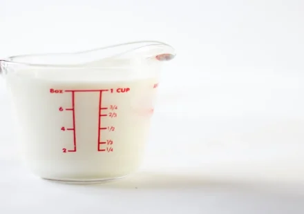 Transparent measuring jug showing cup and liter measurements for volume conversion.