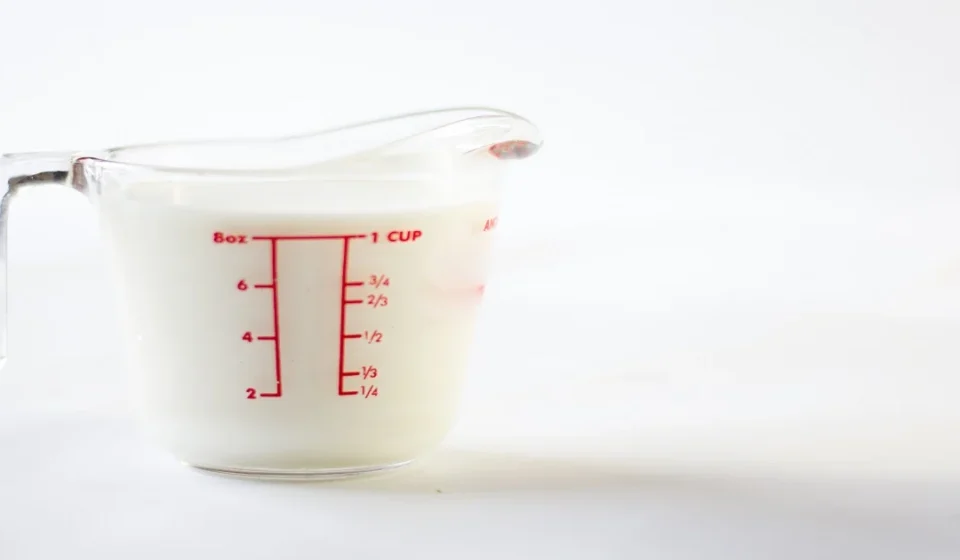 Transparent measuring jug showing cup and liter measurements for volume conversion.