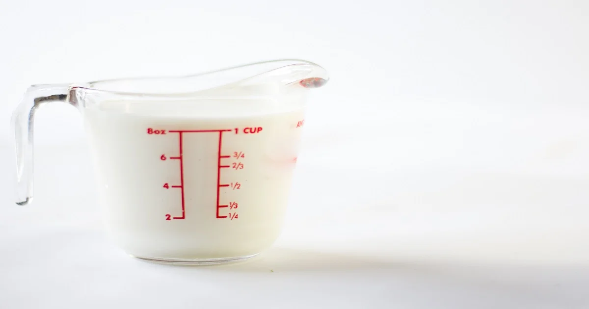 Transparent measuring jug showing cup and liter measurements for volume conversion.